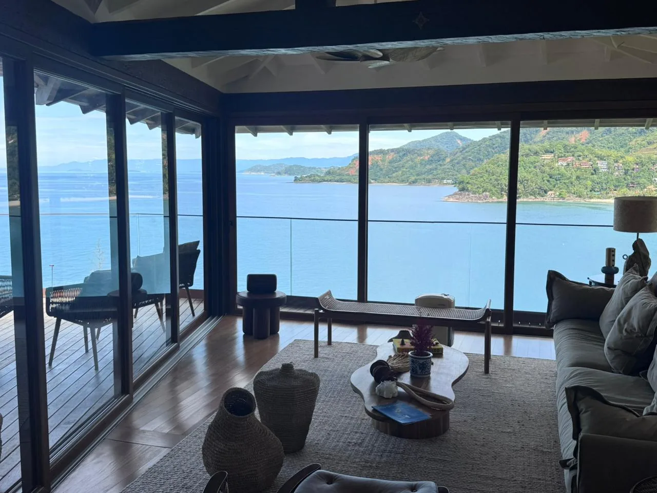 Living com vista para o mar através de grandes panos de vidro