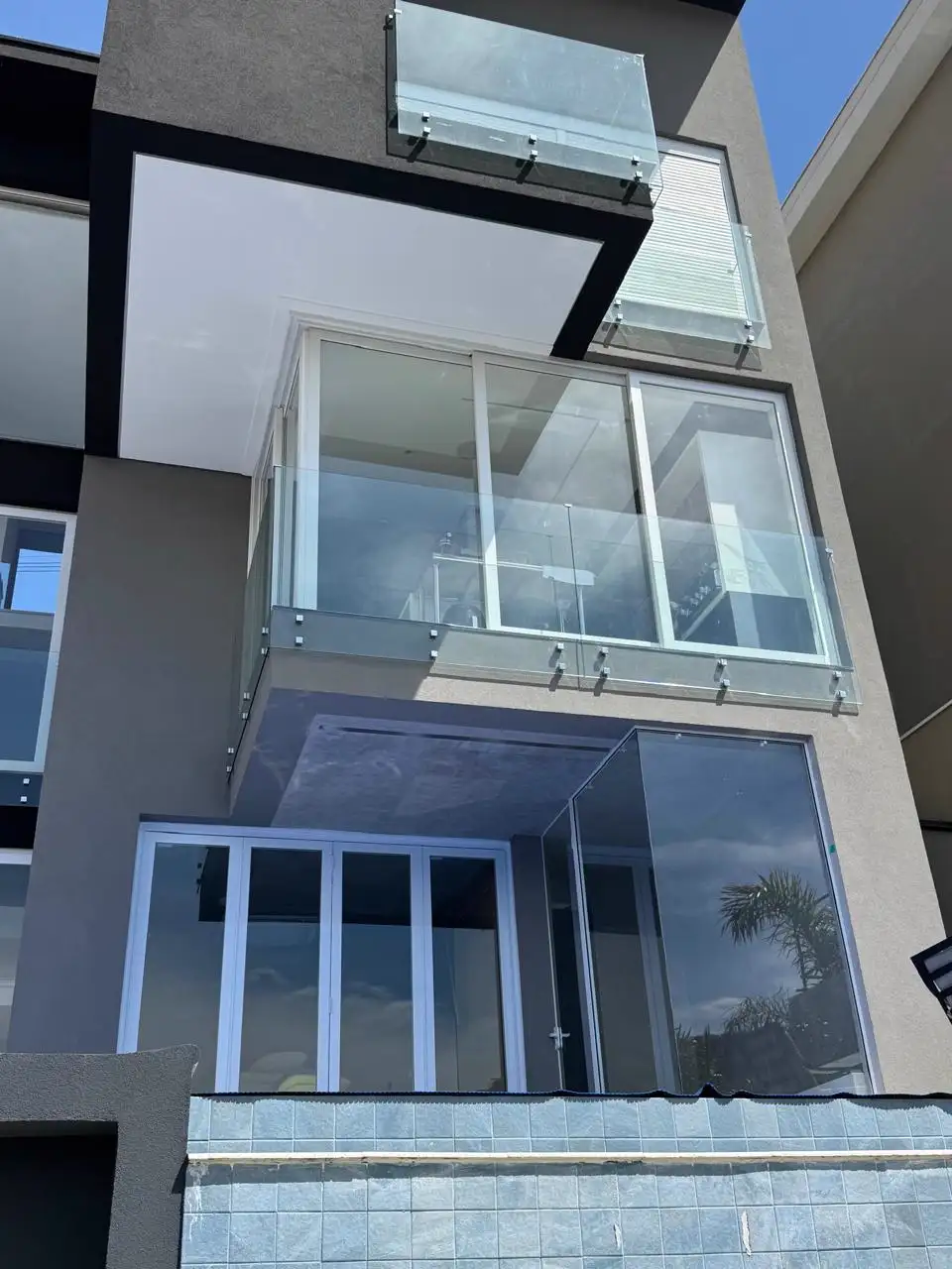 Fachada contemporânea com esquadrias de PVC em perfil escuro e grandes panos de vidro